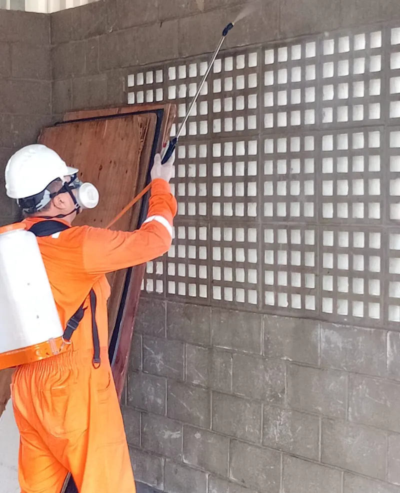 Técnico da PJO com macacão e capacete em aplicação na parede externa de um imóvel